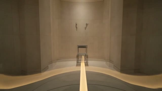 A single chair at the end of a warm path in a quiet room